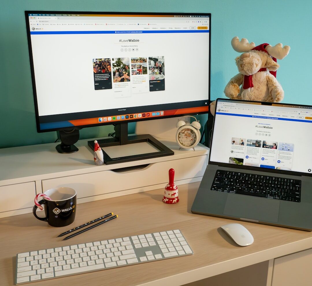 Programmer typing code on a laptop at a desk with a second monitor
