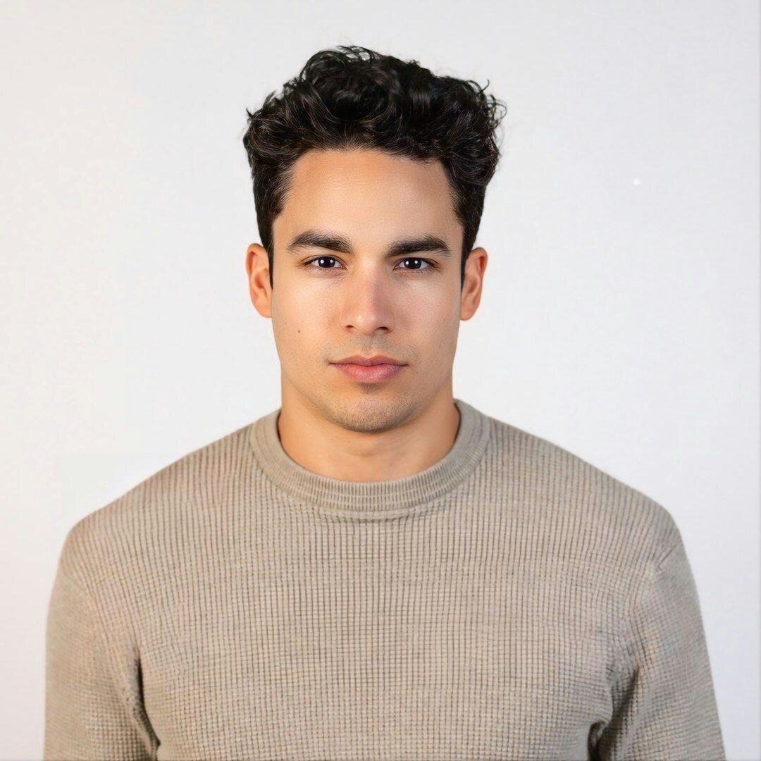Studio portrait of a young man with curly hair smiling at the camera