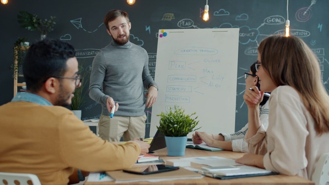 Two colleagues discussing a diagram in front of a whiteboard with notes